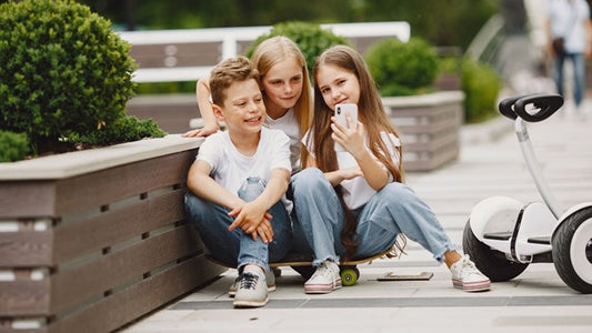 Three kids sitting at road side with rideo hoverboard