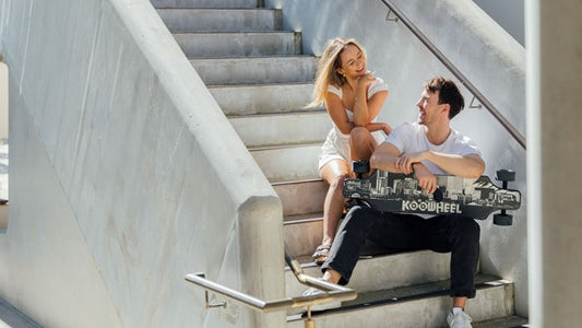 Two people sitting on stair holding rideo electric skateboard