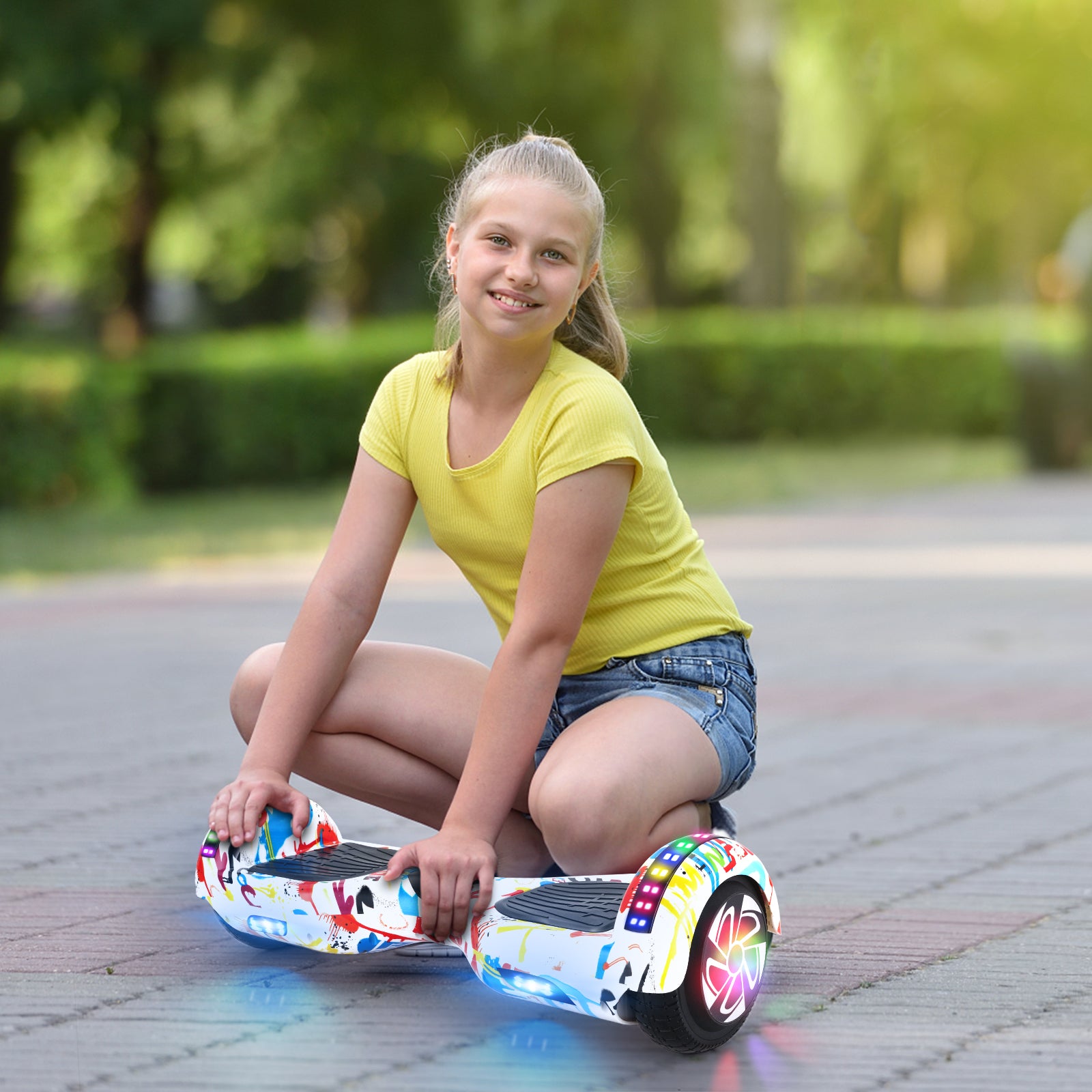 Photo of a young girl sitting next to her RIDEO Hoverboard in White Graffiti, highlighting the hoverboard’s appeal to children and teens