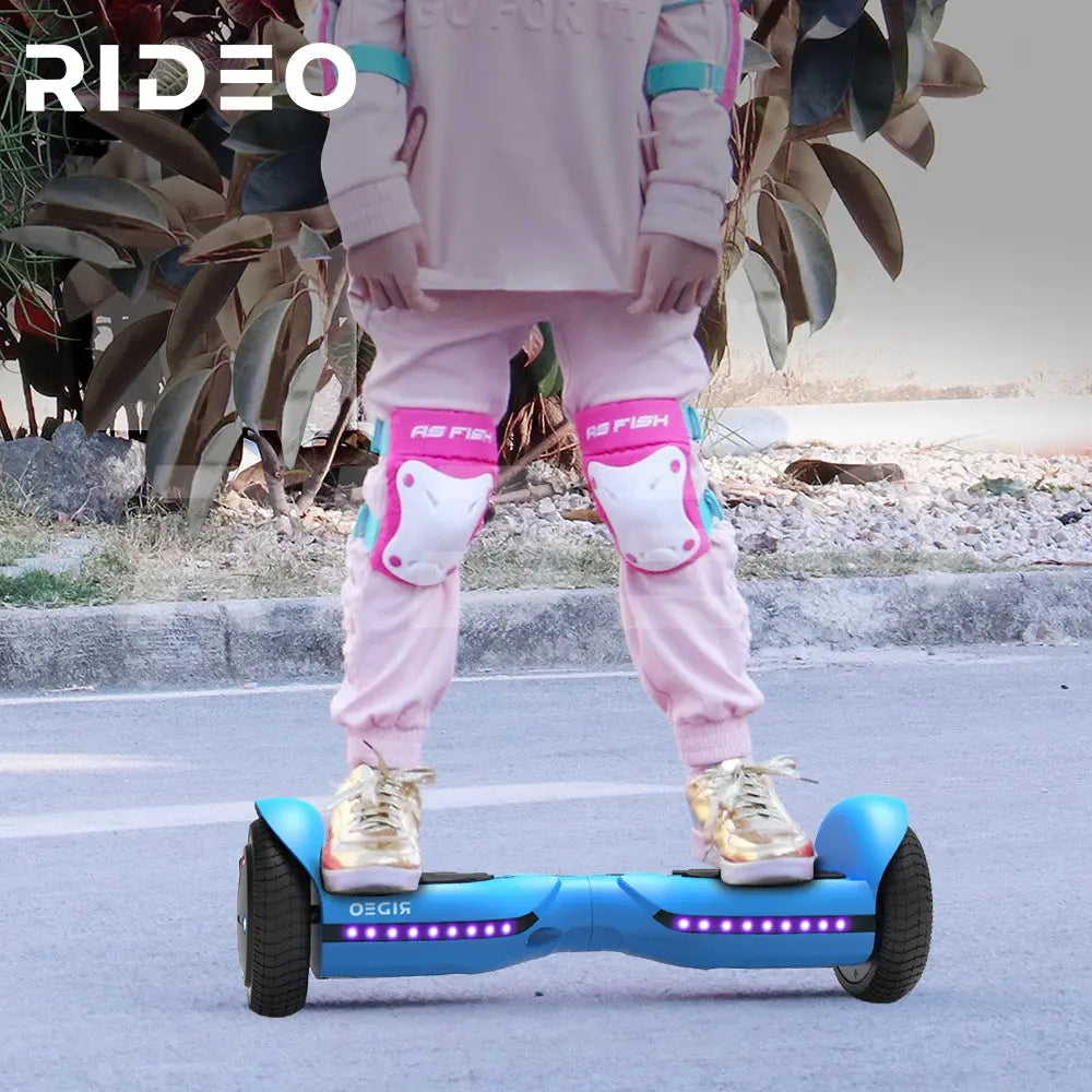 Child riding a RIDEO Q3c Hoverboard in blue, wearing pink safety gear, demonstrating the hoverboard's stability and safety for kids during outdoor play.