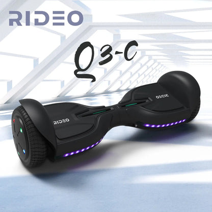 Dynamic portrayal of a black RIDEO Q3-C hoverboard in a modern, architectural environment, highlighting its sleek design and vibrant undercarriage lighting.